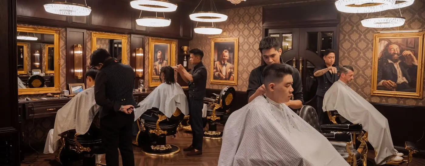 Barbers cutting hair at gilded chairs in the House of Barbaard barbershop